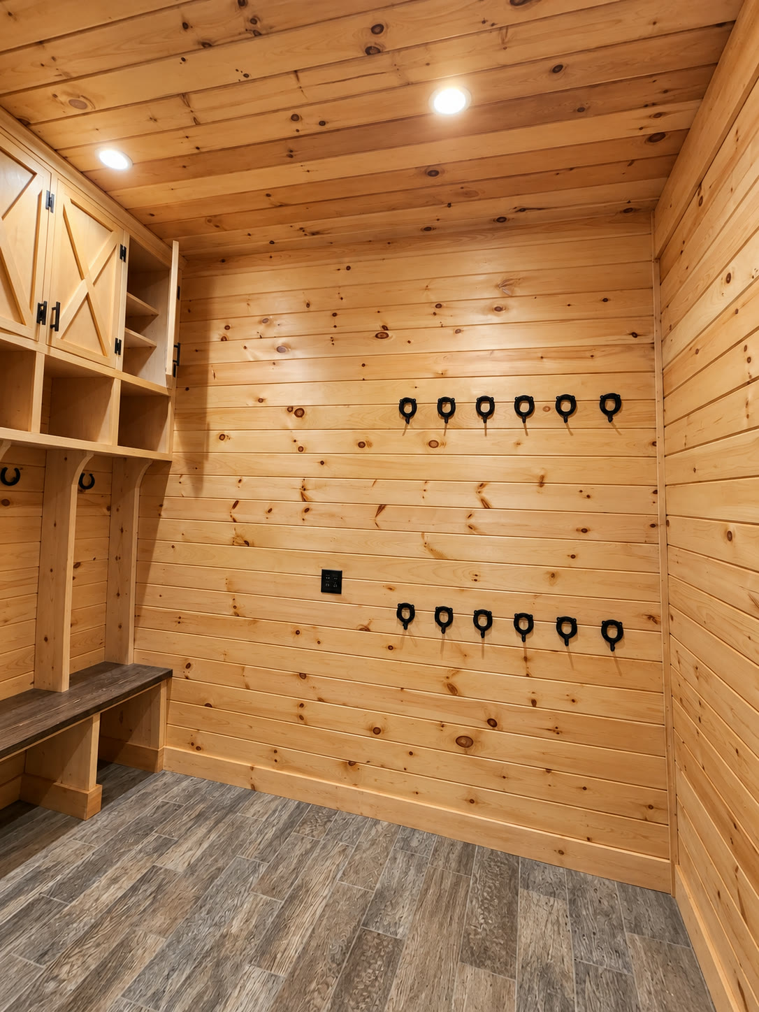 Stained knotty pine tack room with horseshoe hardware hooks