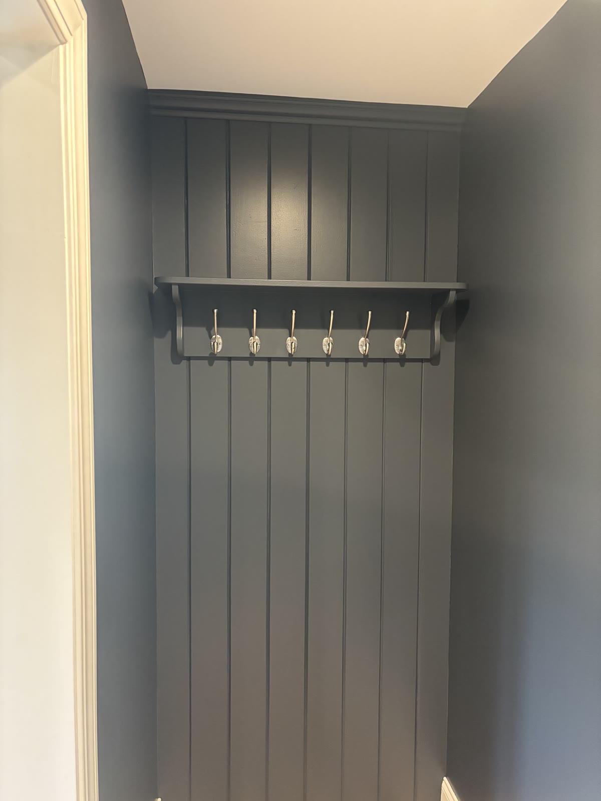 Finished charcoal-blue mudroom nook with hooks