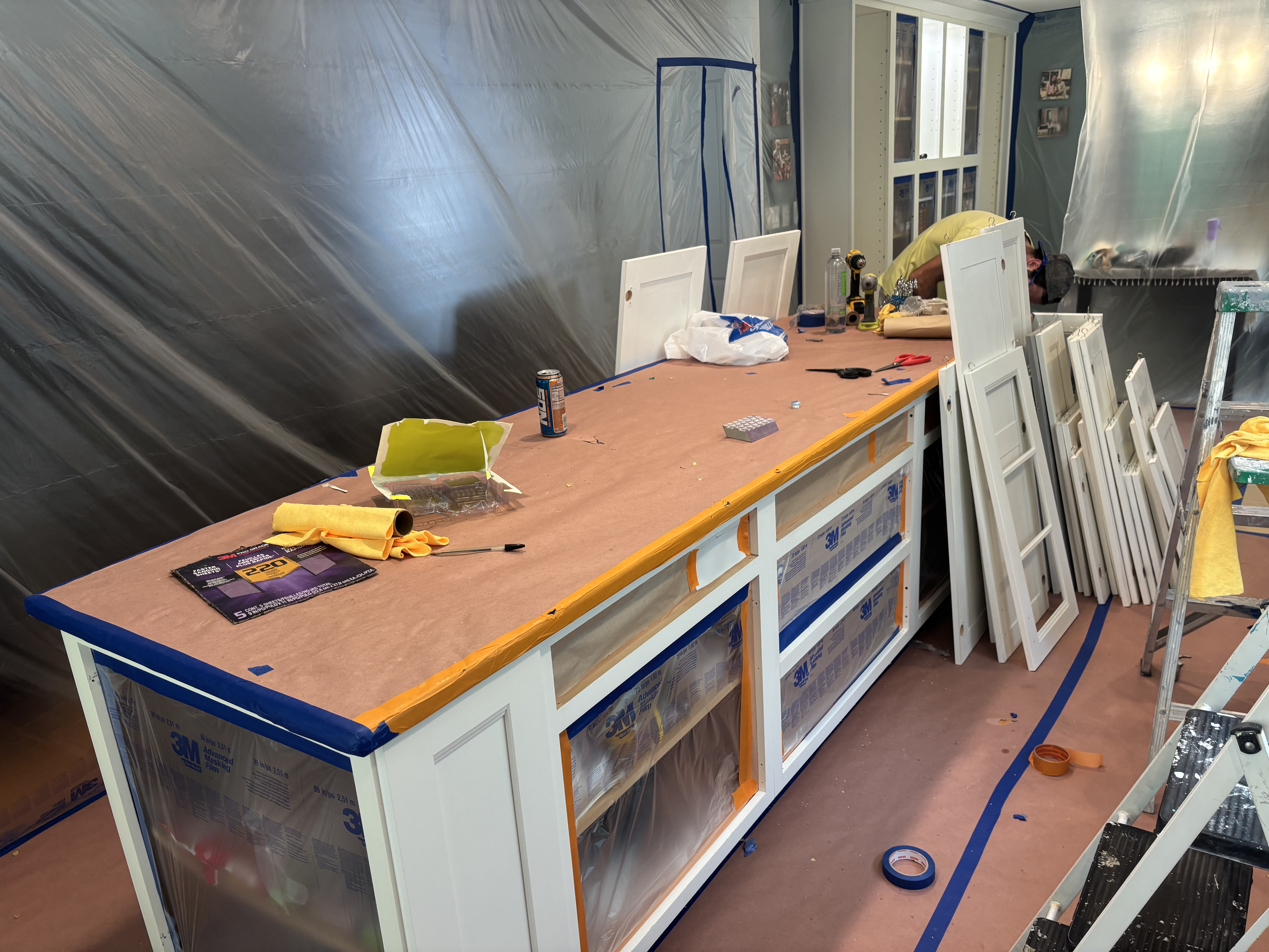 Cabinet painting in progress with surfaces protected